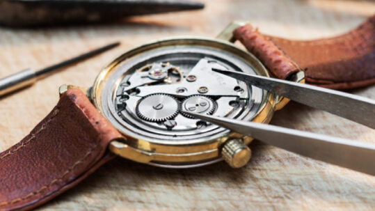 Watch positioned facedown on a soft material in the process of being repaired